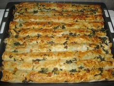 a casserole dish with cheese and spinach in it on a stove top