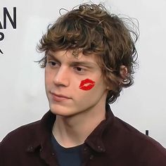 a young man with red lipstick painted on his face