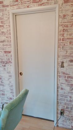 a chair sitting in front of a white door next to a brick wall and wooden floor