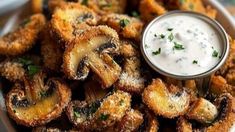 some fried food is on a plate with a small bowl of ranch dressing next to it