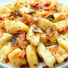 a white plate topped with ravioli and cheese covered in sauces, garnished with parsley