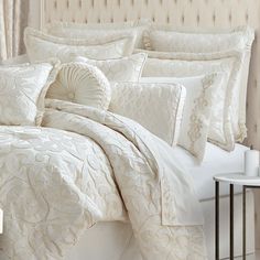 a bed with white comforters and pillows in a room