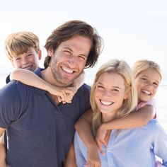 a man and two women hugging each other with their arms around one another on the beach