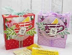 two small gift bags with tags on them and some candy bar wrappers in front of them