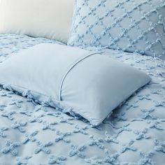 a bed with blue comforters and pillows on it