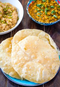 three different types of food are on the wooden table, including pita bread and chickpeas