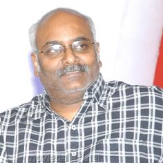 a man with glasses and a plaid shirt is looking at the camera while standing in front of an american flag