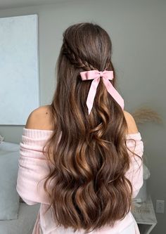 a woman with long brown hair wearing a pink bow