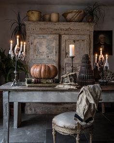 a dining room table with candles and pumpkins on it, next to an old cabinet