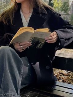 a woman sitting on a bench reading a book