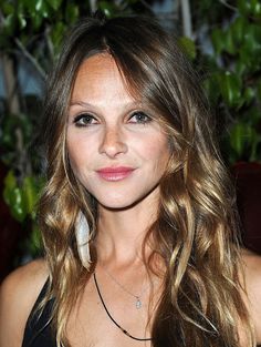 a close up of a person with long hair wearing a black top and necklaces