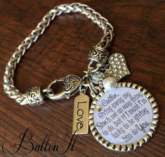 a silver bracelet with a tag on it and some charms attached to the clasps