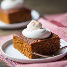 a piece of cake with whipped cream on top is sitting on a plate next to a fork