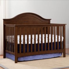 a baby crib with blue and white bedding on the bottom row, in front of a window