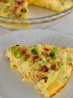 a slice of quiche on a white plate with a glass dish in the background