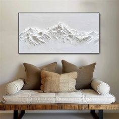 a couch with pillows on it in front of a wall mounted art piece that looks like a mountain range