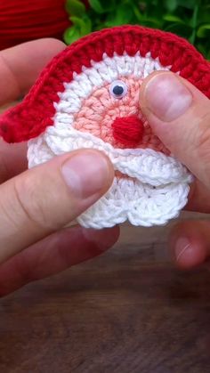 someone is holding a crocheted santa clause ornament