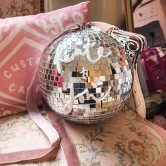 a disco ball purse sitting on top of a chair next to a pillow and pillows