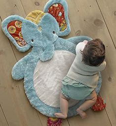 a baby playing with an elephant rug on the floor