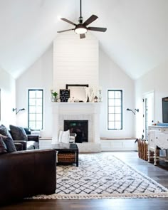 a living room with couches, chairs and a ceiling fan in the middle of it