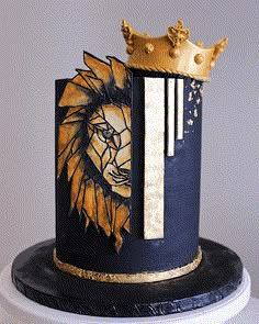 a black and gold cake with a lion on it's side, topped with a crown