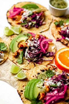 three tacos with different toppings on top of each other and an orange slice