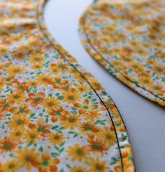 an orange and yellow flowered dress is laying on the table next to it's zipper