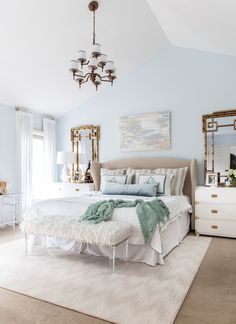 a bedroom with a bed, dresser and chandelier hanging from the ceiling in front of a window