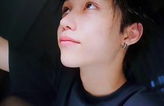 a woman with black hair and piercings on her ear looking up to the sky