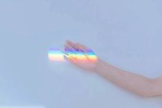 a woman holding out her hand with a rainbow painted on it