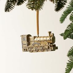 a train ornament hanging from a christmas tree with pine branches in the background