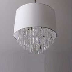 a white chandelier hanging from a ceiling in a room with grey walls and flooring