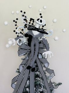 a decorated christmas tree with black and white ribbons on it's top, next to a skull ornament