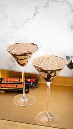 two martini glasses filled with chocolate and oatmeal toppings on a counter