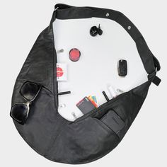 an overhead view of a black bag with sunglasses, cell phone and other items in it