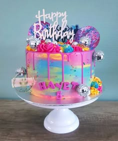 a colorful birthday cake with balloons and confetti on the top that says happy birthday