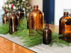 several brown glass bottles sitting on top of a wooden table next to a christmas tree