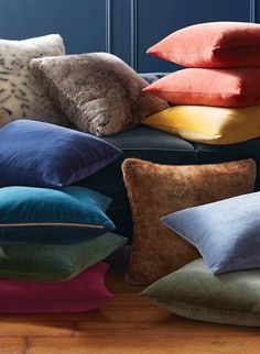 a pile of pillows sitting on top of a wooden floor next to a blue wall