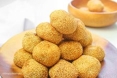 a pile of sesame seeds sitting on top of a wooden plate next to a bowl