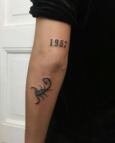 a man with a tattoo on his arm that reads 1932 and has a scorpion in it