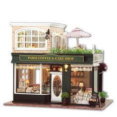 a doll house is set up to look like a paris coffee and cake shop with flowers on the roof