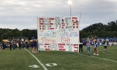 a group of people standing on top of a football field holding up a large sign