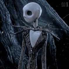 a creepy skeleton dressed in striped clothes standing next to a large rock with spider webs on it's head