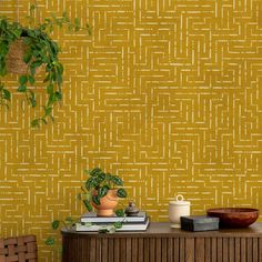 a room with a table, potted plant and yellow wallpaper on the wall