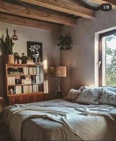 a bed sitting under a window next to a book shelf filled with lots of books