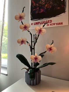 a vase filled with flowers sitting on top of a table next to a painting and lamp