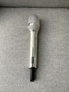 a silver microphone sitting on top of a gray couch