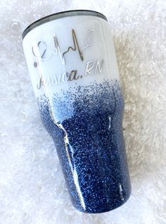 a blue and white tumbler with the word california on it sitting on a fluffy surface