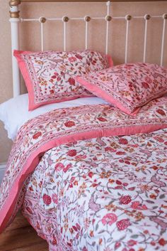 a bed with pink and white bedspread and pillows