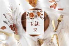 the table number is displayed on a card surrounded by autumn leaves and gold cutlery